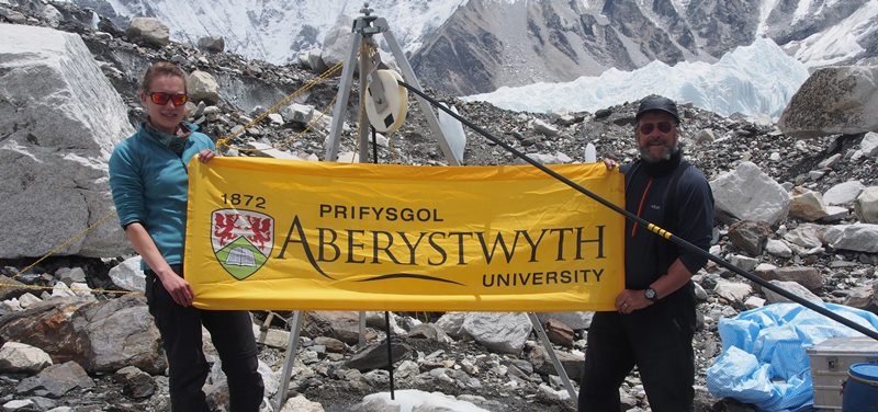 Katie Miles a’r Athro Bryn Hubbard, aelodau Prifysgol Aberystwyth o brosiect EverDrill, yn chwifio baner Aber ar safle rhif tri y tyllu ar rewlif Khumbu wrth droed Everest yn ystod taith 2017.