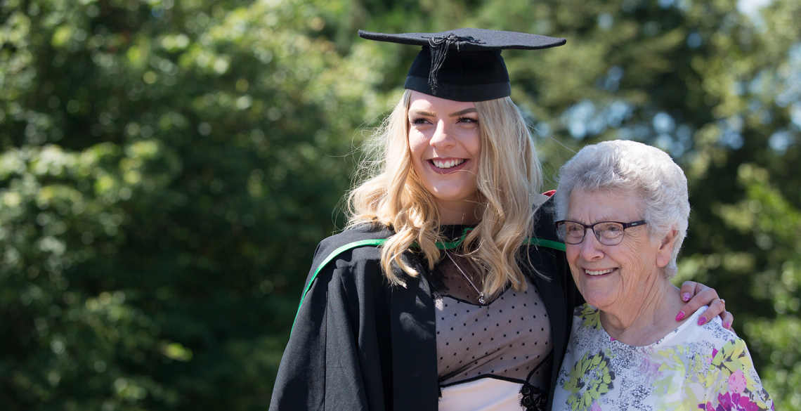 Female student in graduation gowns with her grandmother
