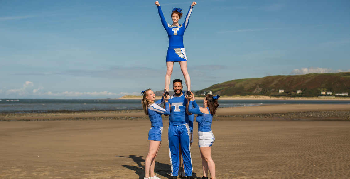 4 cheerleaders in pyramid position on the beach