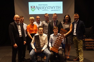 Thomas Rees-Jones and Aaron Bull holding their winning lamps alongside the Dragons and staff from Aberystwyth University