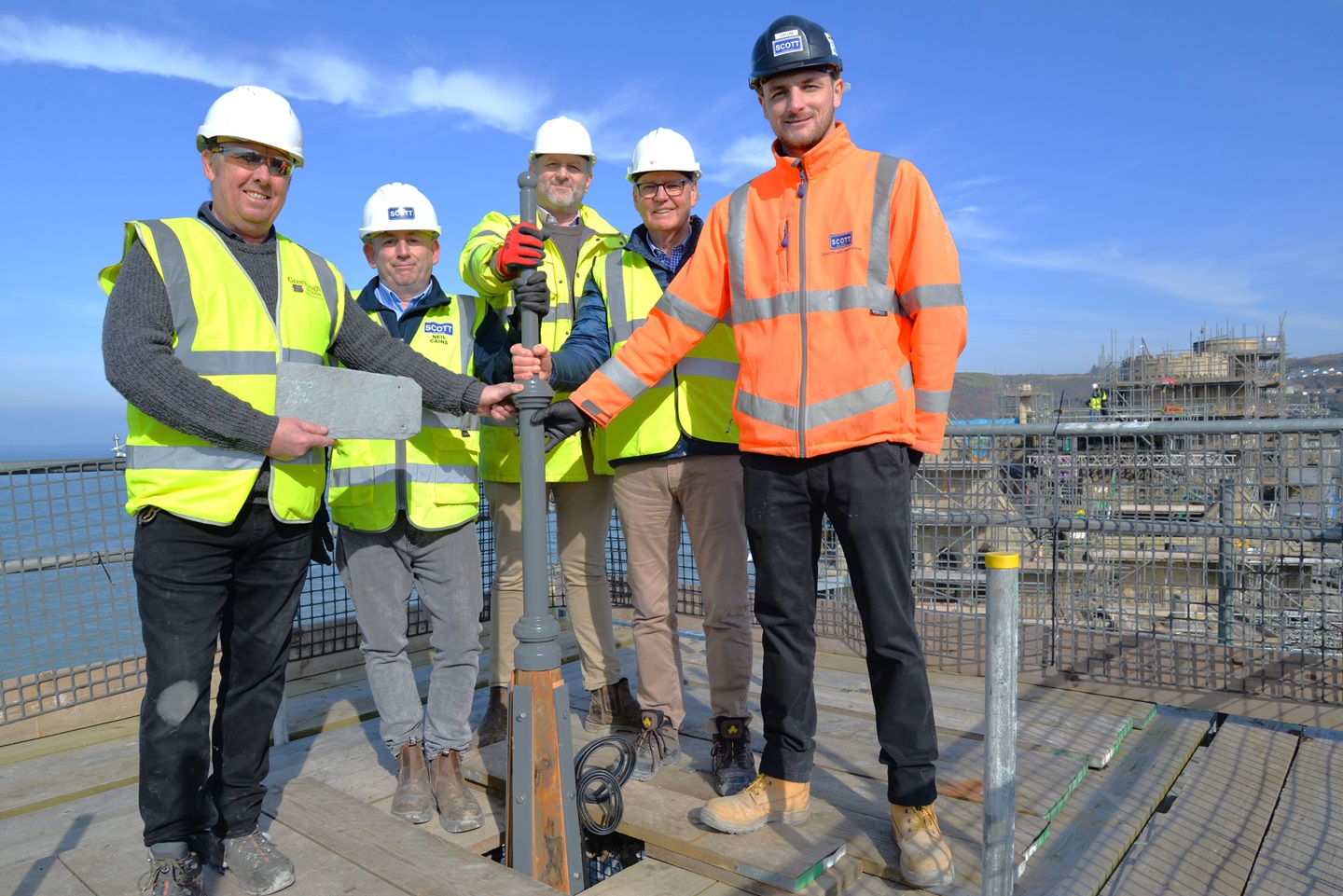 Marking the placing of the final slate on the turrets of South Seddon of Old College, 5 March 2025. Left to right; Jon Greenough (Greenough & Sons); Neil Cains (Andrew Scott Ltd); Matthew Dyer (Austin Smith Lord), Jim O’Rourke (Aberystwyth University) and Calum Duncan (Andrew Scott) stand next to the new finial on the main South Seddon turret of Aberystwyth University’s Old College. Copyright Andrew Scott Ltd